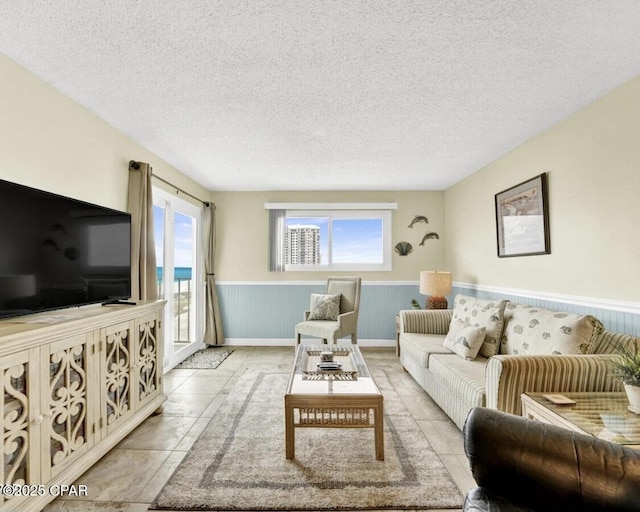 tiled living area with a wainscoted wall and a textured ceiling