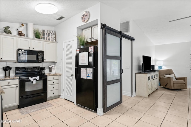 kitchen with backsplash, a barn door, white cabinetry, and black appliances