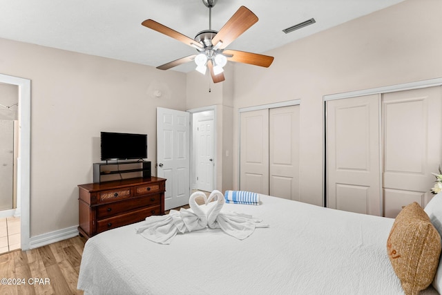 bedroom featuring ceiling fan, two closets, and light wood-type flooring