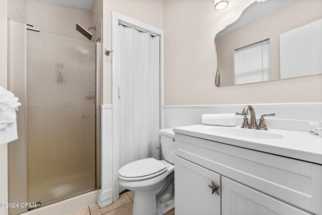 bathroom with tile patterned flooring, vanity, toilet, and a shower with door