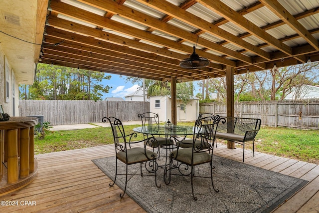 wooden deck featuring a shed, ceiling fan, and a lawn