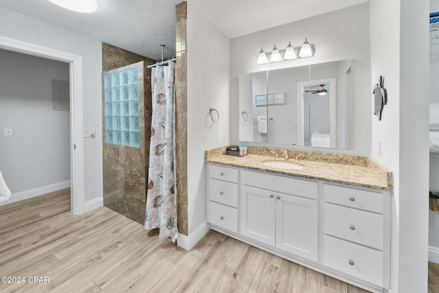 bathroom with a shower with shower curtain, vanity, a textured ceiling, ceiling fan, and hardwood / wood-style floors