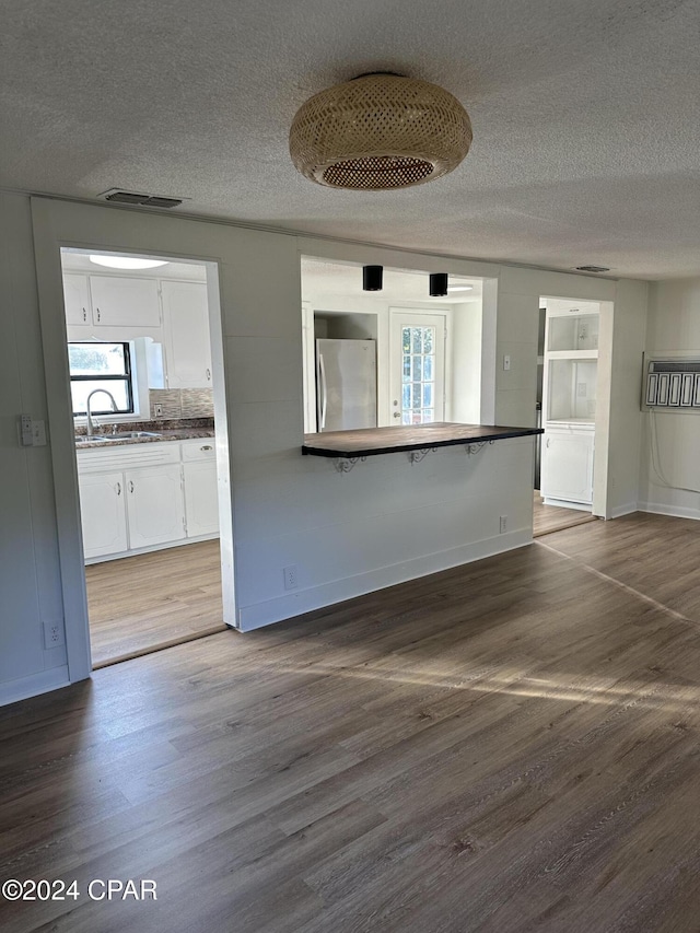 unfurnished living room with a textured ceiling, dark hardwood / wood-style floors, and sink