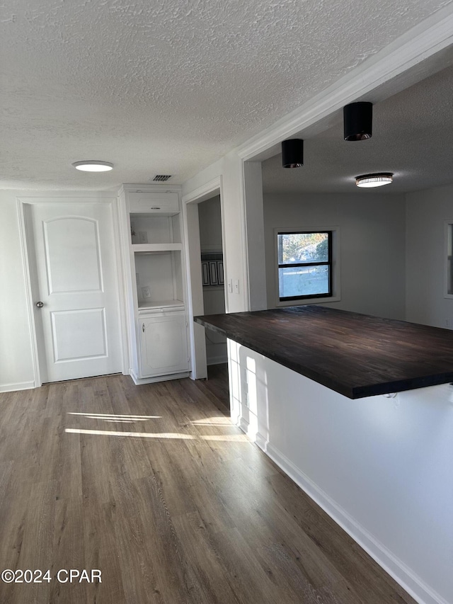 interior space with hardwood / wood-style flooring, a textured ceiling, and wood counters