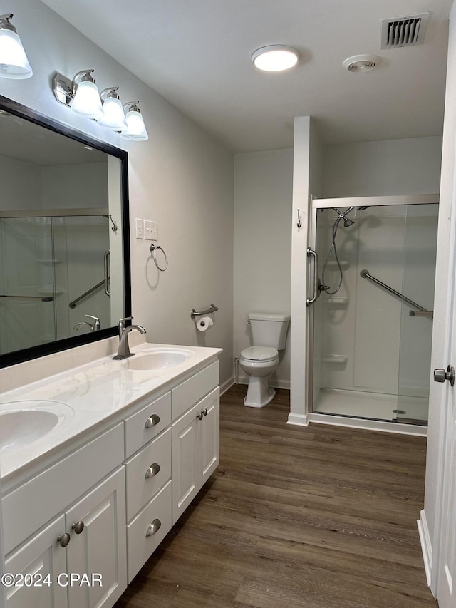 bathroom with wood-type flooring, vanity, toilet, and a shower with door