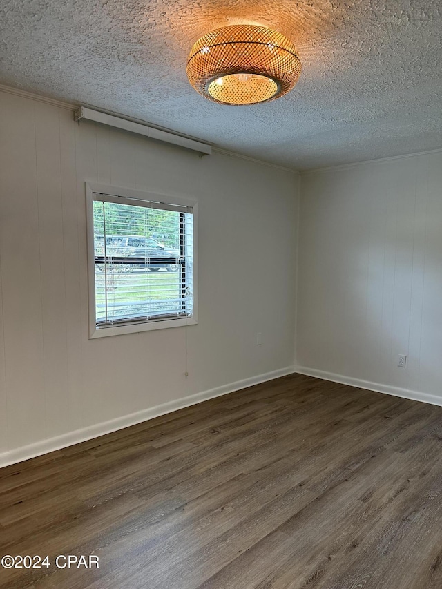 spare room featuring wood walls, dark hardwood / wood-style flooring, and a textured ceiling