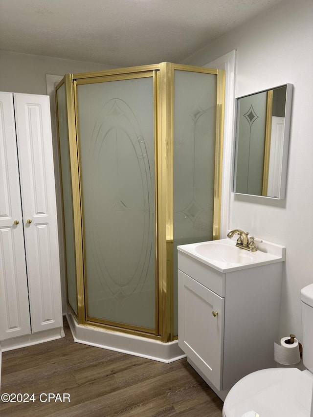 bathroom featuring a shower with shower door, toilet, wood-type flooring, and vanity