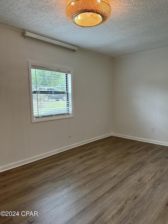 empty room with dark hardwood / wood-style flooring, a textured ceiling, and wooden walls