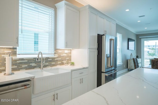 kitchen with tasteful backsplash, stainless steel appliances, light stone counters, and white cabinetry