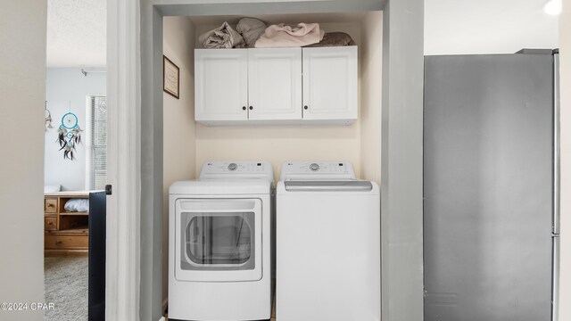 laundry area featuring cabinets, carpet floors, and washing machine and clothes dryer