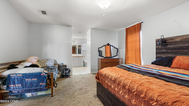 bedroom featuring connected bathroom, light colored carpet, and a textured ceiling