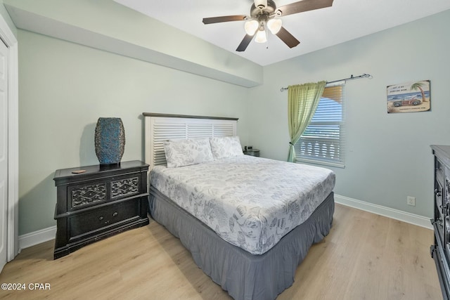 bedroom with ceiling fan, light wood-style flooring, and baseboards