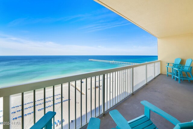 balcony featuring a view of the beach and a water view