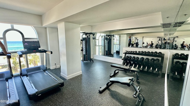 workout area featuring a water view and baseboards