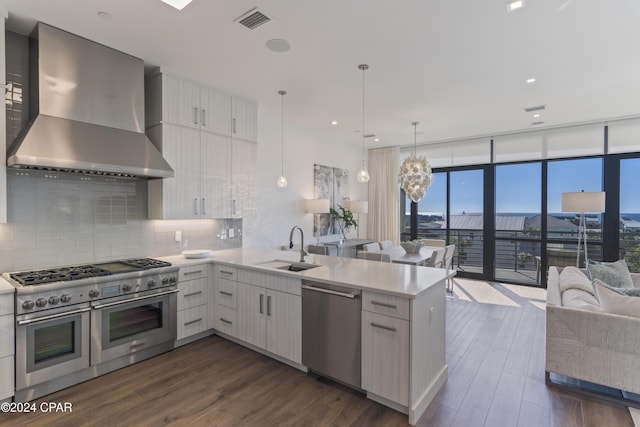 kitchen with kitchen peninsula, sink, wall chimney exhaust hood, and appliances with stainless steel finishes