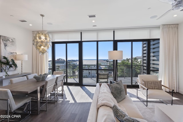 living room featuring hardwood / wood-style floors, ceiling fan with notable chandelier, and expansive windows