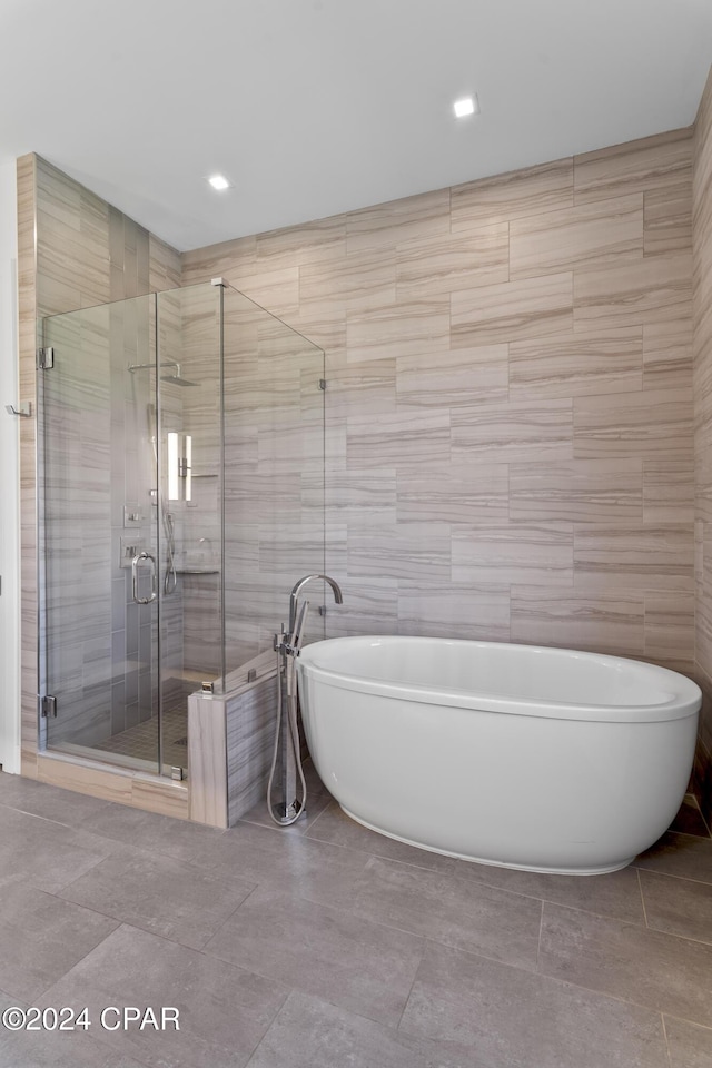 bathroom with separate shower and tub and tile walls