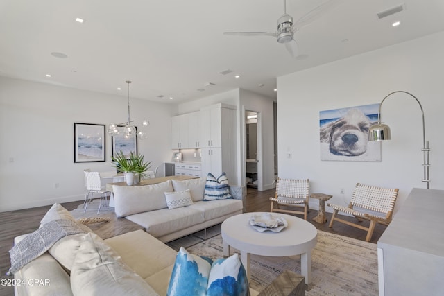 living room with ceiling fan with notable chandelier and hardwood / wood-style flooring