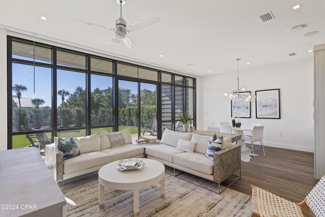 living room with hardwood / wood-style floors, ceiling fan with notable chandelier, a wall of windows, and a wealth of natural light