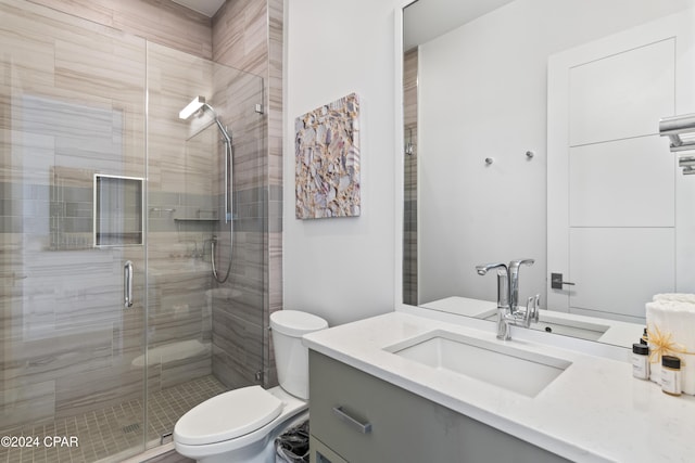 bathroom with vanity, toilet, and a shower with door