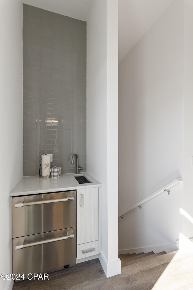 bar featuring sink, light wood-type flooring, and backsplash