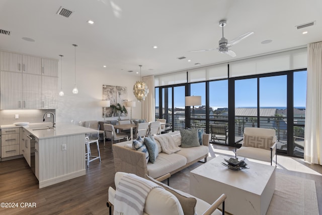 living room featuring sink, expansive windows, dark hardwood / wood-style floors, and ceiling fan with notable chandelier