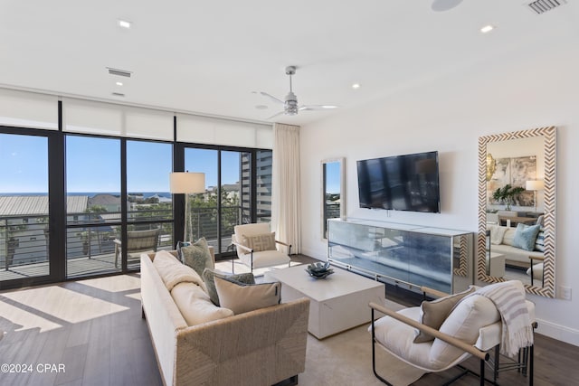 living room featuring ceiling fan, hardwood / wood-style floors, and a wall of windows