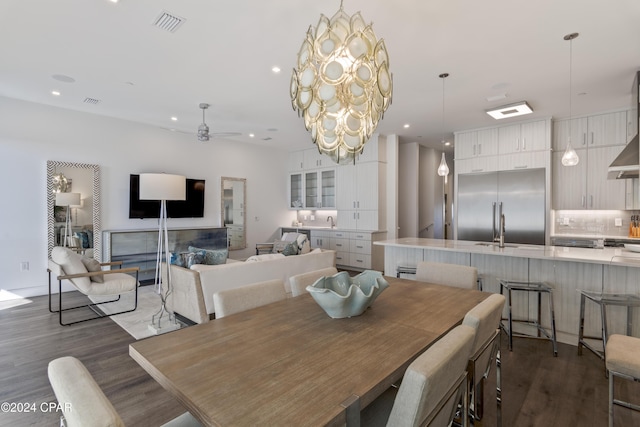 dining area with ceiling fan with notable chandelier, dark hardwood / wood-style flooring, and sink