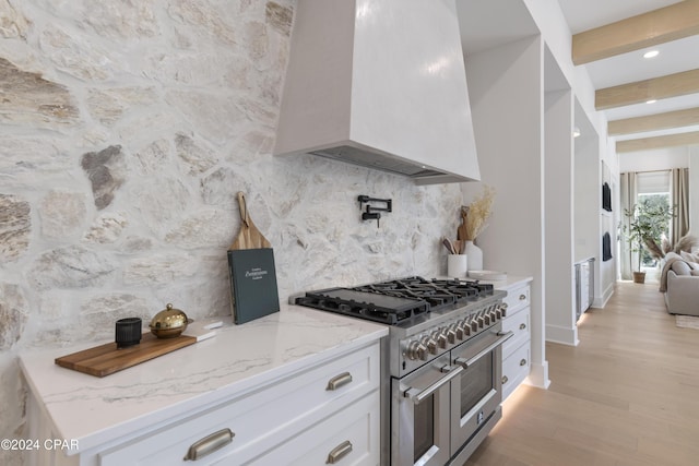 kitchen with white cabinetry, double oven range, light hardwood / wood-style floors, and custom exhaust hood