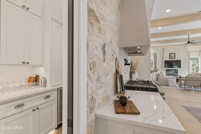 kitchen featuring island exhaust hood, light stone countertops, stainless steel range, light hardwood / wood-style floors, and white cabinetry