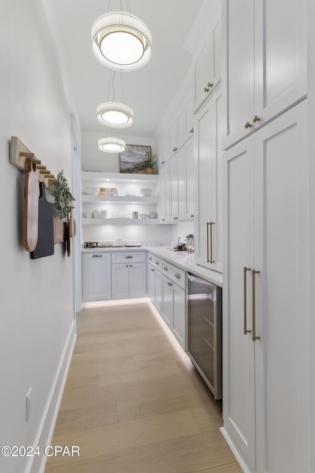 kitchen featuring white cabinets, decorative light fixtures, light hardwood / wood-style floors, and beverage cooler