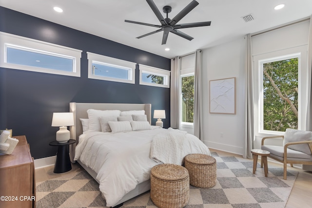 bedroom with multiple windows, ceiling fan, and light wood-type flooring