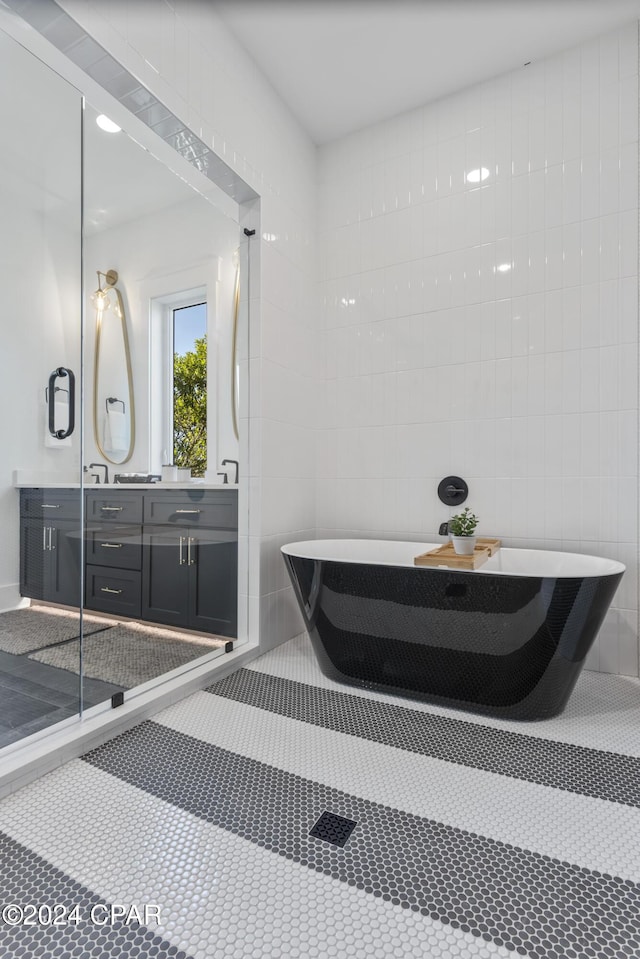 bathroom with vanity, tile patterned floors, tile walls, and a tub