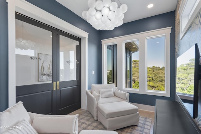 living area featuring french doors, a wealth of natural light, and an inviting chandelier