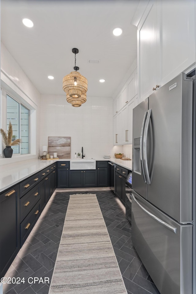 kitchen with decorative light fixtures, white cabinetry, stainless steel fridge with ice dispenser, and sink