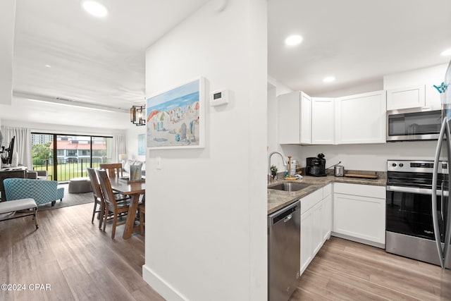 kitchen featuring white cabinets, sink, light hardwood / wood-style flooring, dark stone countertops, and appliances with stainless steel finishes