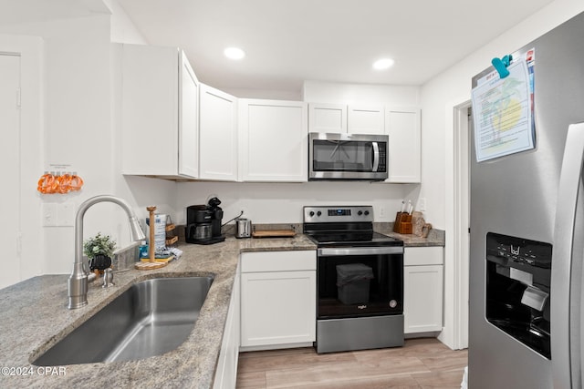 kitchen featuring light stone countertops, white cabinetry, sink, stainless steel appliances, and light wood-type flooring