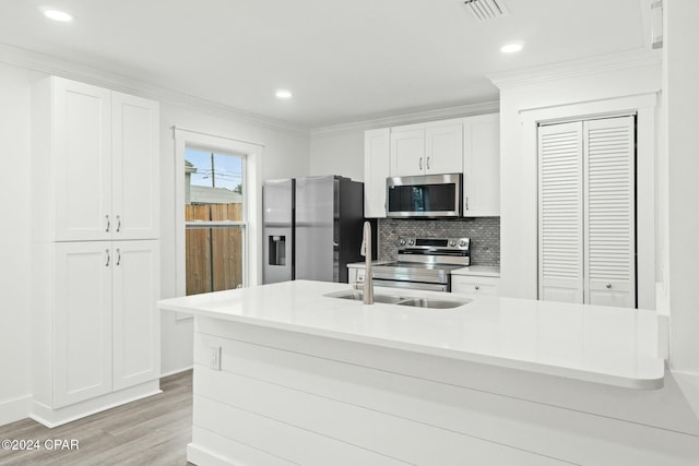 kitchen featuring white cabinetry, stainless steel appliances, tasteful backsplash, light wood-type flooring, and sink