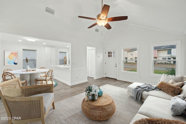 living area featuring baseboards, visible vents, high vaulted ceiling, ceiling fan, and light wood-style floors