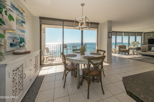 dining area with a water view, a notable chandelier, expansive windows, and light tile patterned floors