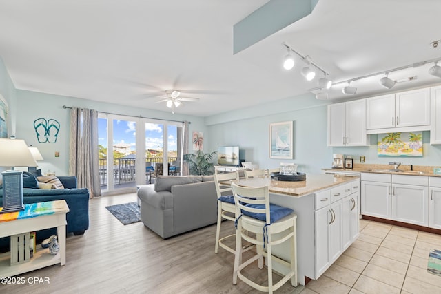 kitchen with a breakfast bar, a kitchen island, ceiling fan, sink, and white cabinetry