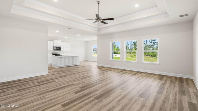 interior space featuring light wood-type flooring, crown molding, and a tray ceiling