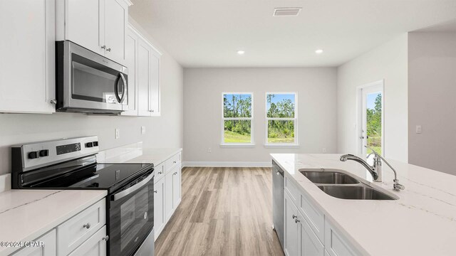 kitchen featuring white cabinetry, a kitchen island with sink, light hardwood / wood-style flooring, and stainless steel appliances