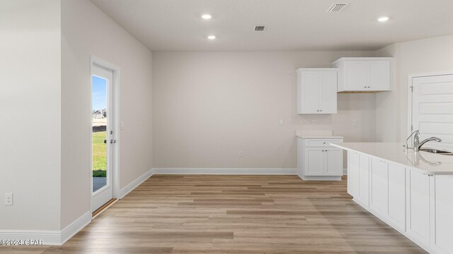 kitchen with a center island with sink, sink, appliances with stainless steel finishes, dark hardwood / wood-style flooring, and white cabinetry