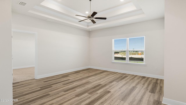 spare room featuring light wood-type flooring, a tray ceiling, ceiling fan, and crown molding