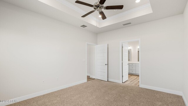 spare room with a tray ceiling, ceiling fan, carpet, and ornamental molding