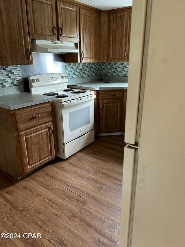 kitchen featuring backsplash, light hardwood / wood-style flooring, and white electric range oven