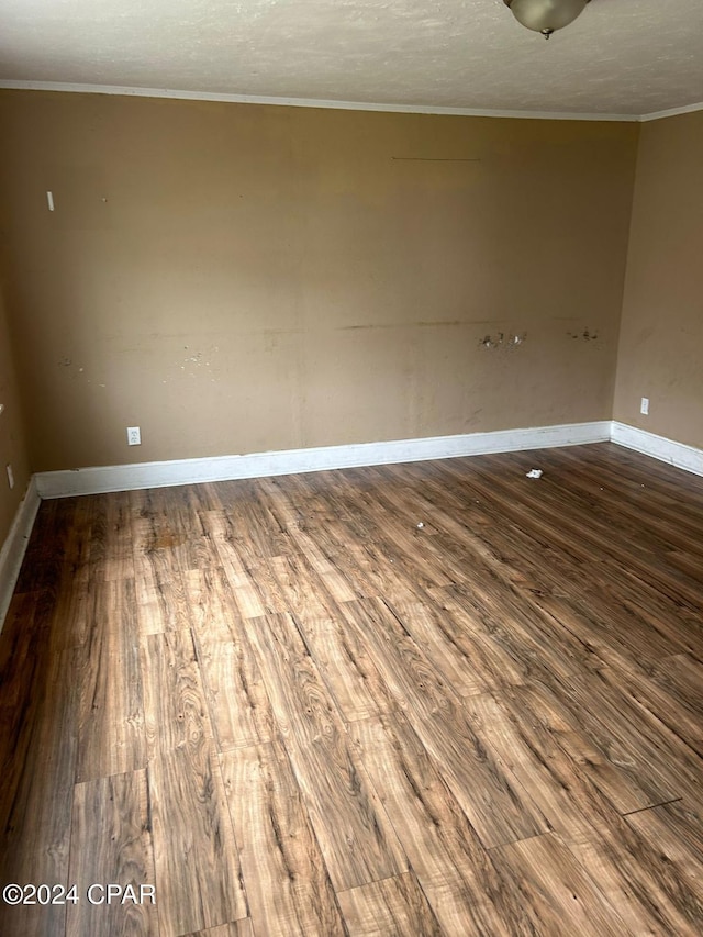 spare room with crown molding, wood-type flooring, and a textured ceiling