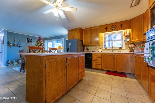 kitchen featuring tasteful backsplash, ceiling fan, a kitchen island, and stainless steel refrigerator with ice dispenser