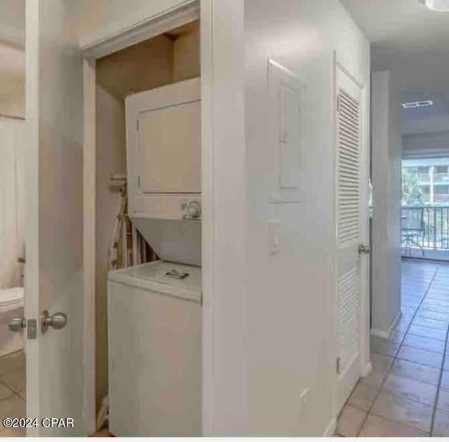 clothes washing area featuring light tile patterned floors and stacked washer / drying machine